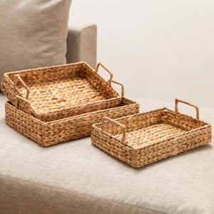 Könnte beinhalten: Drei geflochtene Weidenkörbe mit Griffen, ineinander verschachtelt. Die Körbe sind aus natürlichen Materialien gefertigt und haben eine hellbraune Farbe.