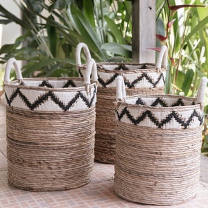 Puede incluir: Tres cestas tejidas con patrones de chevron en blanco y negro. Las cestas están hechas de materiales naturales y tienen un aspecto rústico.