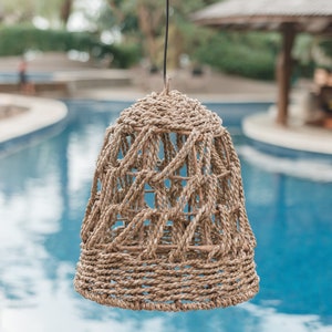 May include: A woven, tan, rope light fixture hanging over a blue pool
