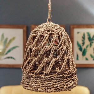 May include: A woven, light brown, lampshade hanging from a ceiling. The lampshade is made of a natural material and has a unique, intricate design.