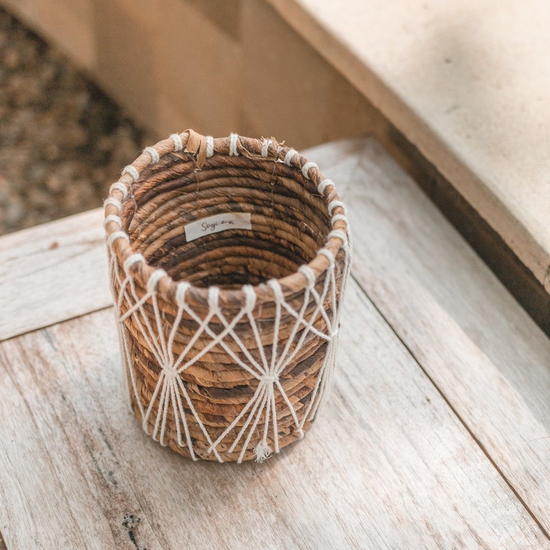 May include: A woven brown and white planter with a label that says "Sage One".