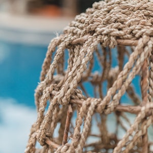 May include: Close-up of a woven basket made of natural brown fibers. The basket is made of a thick, braided rope that is woven into a tight, intricate pattern. The basket is a light brown color and has a natural, rustic look.