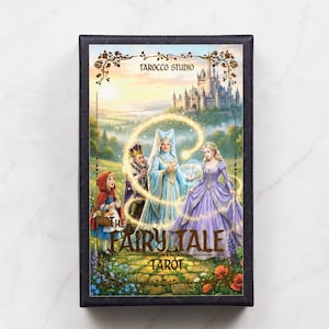 Pu&ograve; includere: Scatola di carte dei tarocchi con un'illustrazione fantasy. La scatola presenta una scena fiabesca con personaggi come Cappuccetto Rosso, una regina e un castello. Il testo "The Fairy Tale Tarot" &egrave; visualizzato.