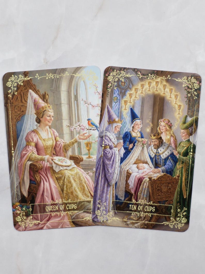 Pu&ograve; includere: Due carte dei tarocchi con illustrazioni di reali. La carta "Queen of Cups" raffigura una donna in abito rosa e oro, mentre la carta "Ten of Cups" mostra una famiglia reale con un bambino. Entrambe le carte hanno bordi floreali e testo.