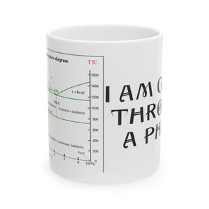 Op de afbeelding: Witte keramische mok met een zwarte en groene afbeelding met de tekst "Ik ga door een fase". De afbeelding bevat ook een zwart-wit diagram met de tekst "fasediagram" en "T°C".