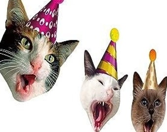 May include: A garland of seven cat faces wearing colorful party hats. The cats have different colored fur and are all looking at the camera with their mouths open.