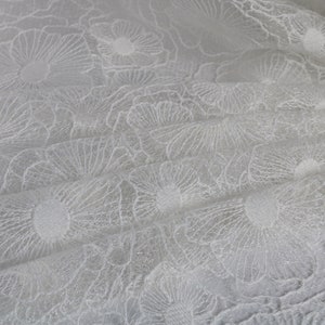Puede incluir: Tela blanca transparente con un delicado patr&oacute;n floral. La tela es texturizada y tiene un brillo sutil.