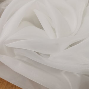 May include: White sheer fabric with a soft, flowing texture. The fabric is translucent and has a subtle sheen.
