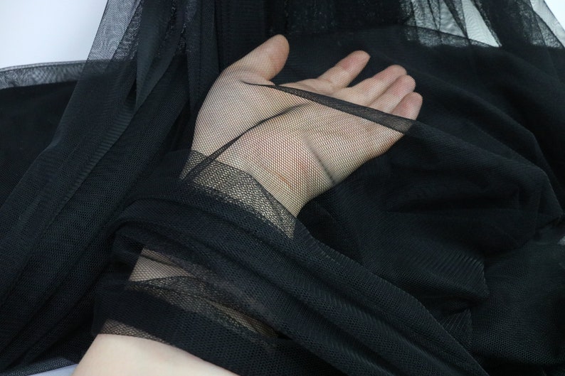 Puede incluir: Primer plano de tela de tul negra. El material transparente est&aacute; drapeado y recogido, revelando la textura y transparencia de la fina malla. La tela es de color negro intenso, adecuada para diversos proyectos de artesan&iacute;a y moda.