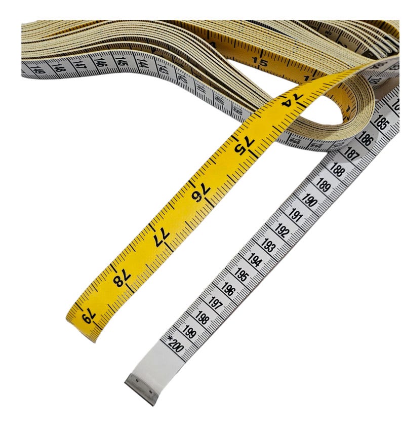 May include: A yellow and white measuring tape with numbers from 74 to 200. The tape is rolled up and the end is visible.