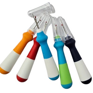 May include: Set of five colorful thread snips with clear plastic caps. Each snip has a white handle and a colored tip. The colors are orange, red, blue, green, and black.