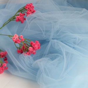 May include: A sprig of pink baby's breath flowers on a light blue tulle fabric.