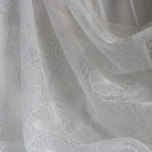 Puede incluir: Tela blanca transparente con un delicado patr&oacute;n floral. La tela es suave y fluida, lo que la hace ideal para una variedad de proyectos de manualidades.