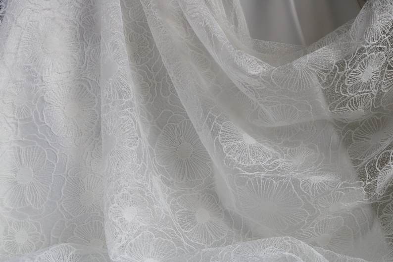 Puede incluir: Tela blanca transparente con un delicado patr&oacute;n floral. La tela es suave y fluida, lo que la hace ideal para una variedad de proyectos de manualidades.