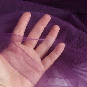 May include: Purple sheer fabric with a fine mesh texture. The fabric is soft and delicate, and it has a slight sheen.