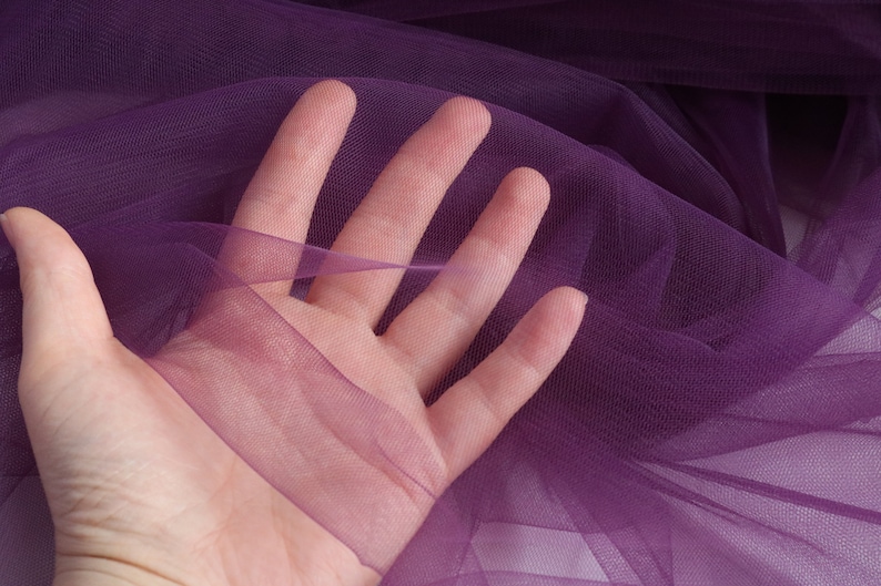 May include: Purple sheer fabric with a fine mesh texture. The fabric is soft and delicate, and it has a slight sheen.
