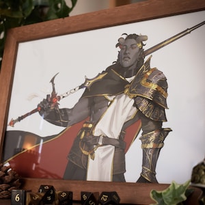 Puede incluir: Una ilustración enmarcada de un personaje de fantasía. El personaje es un humanoide con piel oscura, cuernos y una espada larga. Lleva una armadura negra y dorada con una capa blanca. El fondo es gris claro.