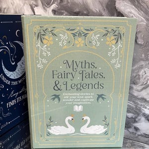 May include: A hardcover book titled "Myths, Fairy Tales, & Legends" with a light green cover. The cover features floral designs, two swans, and the text "Enchanting stories to stir your soul, spark wonder and captivate your imagination."