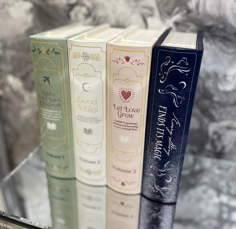 May include: Four hardcover books with decorative spines. The books are in pastel colors: green, cream, pink, and navy blue. The spines feature text and illustrations, including the phrases "Myths, Fairy Tales & Legends", "Good Vibes", "Let Love Grow", and "Finds Its Magic".