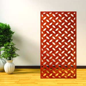 May include: A rust-colored metal screen with a repeating pattern of white oval cutouts. The screen is standing in front of a white wall and a wooden floor.