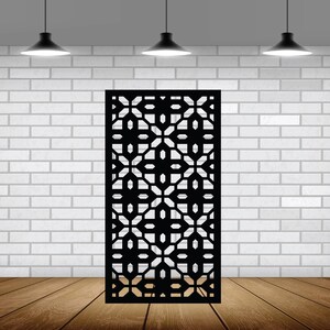 May include: A black metal room divider with a geometric pattern. The divider is standing in front of a white brick wall.