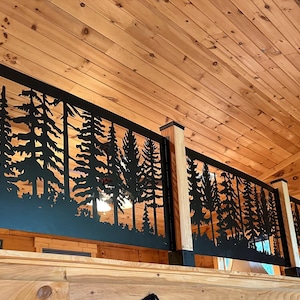 May include: Black metal railing with a cut-out design of pine trees. The railing is installed on a wooden ceiling.