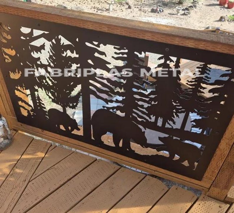 May include: A rectangular black metal panel featuring a laser-cut design of a forest scene with pine trees and three bears. The metal panel is mounted within a wooden frame. The text FABRIPLAS METAL is visible across the center of the panel.