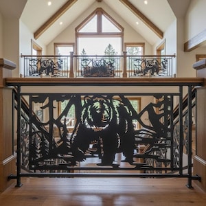 May include: A staircase railing featuring black metal panels with a laser-cut design of a bear standing in a forest. The metal panels are framed by natural wood posts and a matching wooden handrail, creating a sturdy barrier for the interior space.