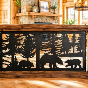 May include: A rectangular black metal panel featuring a laser-cut silhouette of a forest scene with three bears. The panel is framed by dark stained wooden posts and horizontal beams, creating a decorative railing insert for an interior space.