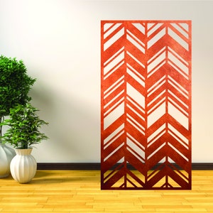May include: A red metal room divider with a chevron pattern. The divider is standing on a wooden floor in front of a white wall.