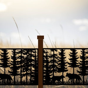 May include: A black metal fence panel with a silhouette design of pine trees and wolves walking through a forest. The fence panel is set against a blurred background of a field of tall grass and a blue sky with white clouds.