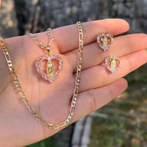 Op de afbeelding: Gouden ketting met een hartvormige hanger met een afbeelding van de Maagd Maria, omringd door roze zirkonia-stenen. Passende hartvormige oorbellen met hetzelfde ontwerp.