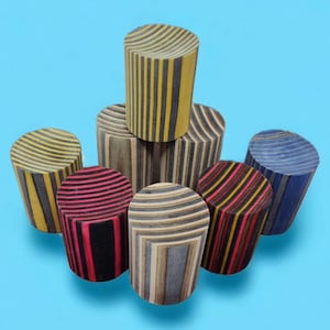 May include: A group of six wooden cylinders with different striped patterns in yellow, black, red, blue, and gray. The cylinders are arranged in a pyramid shape on a blue background.