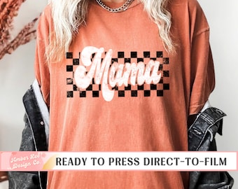 May include: A burnt orange t-shirt with a white "Mama" graphic in a retro font. The graphic is set against a black and white checkered background. The text "READY TO PRESS DIRECT-TO-FILM" is visible at the bottom of the image.