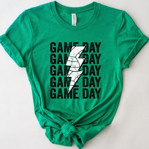 May include: Green t-shirt with a white lightning bolt graphic and the text "GAME DAY" repeated five times.