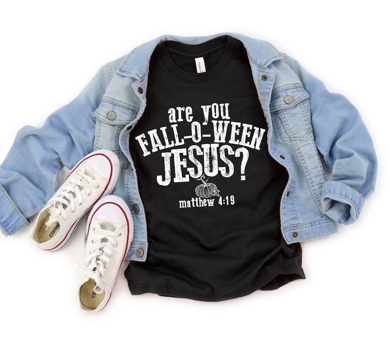 May include: Black t-shirt with the text "are you FALL-O-WEEN JESUS?" and "matthew 4:19" in white. The shirt is paired with a light blue denim jacket and white canvas sneakers with red trim.