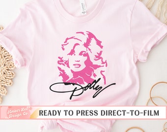 May include: Pink t-shirt with a pink silhouette of Dolly Parton and her signature in black. The text "READY TO PRESS DIRECT-TO-FILM" is at the bottom of the image.
