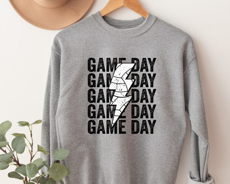 May include: Grey sweatshirt with a white lightning bolt graphic and the text "GAME DAY" repeated five times.