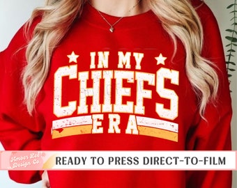 Könnte beinhalten: Roter Pullover mit weißem Text, der "In My Chiefs Era" lautet, mit einem gelben Stern auf jeder Seite des Textes. Der Text hat einen abgenutzten Look. Der Pullover ist bereit zum Bedrucken mit Direct-to-Film.
