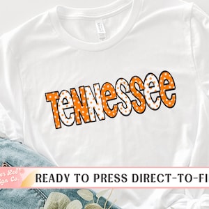 May include: White t-shirt with the word "Tennessee" in orange and white polka dot letters. The text is outlined in black. The shirt is ready to press with direct-to-film.