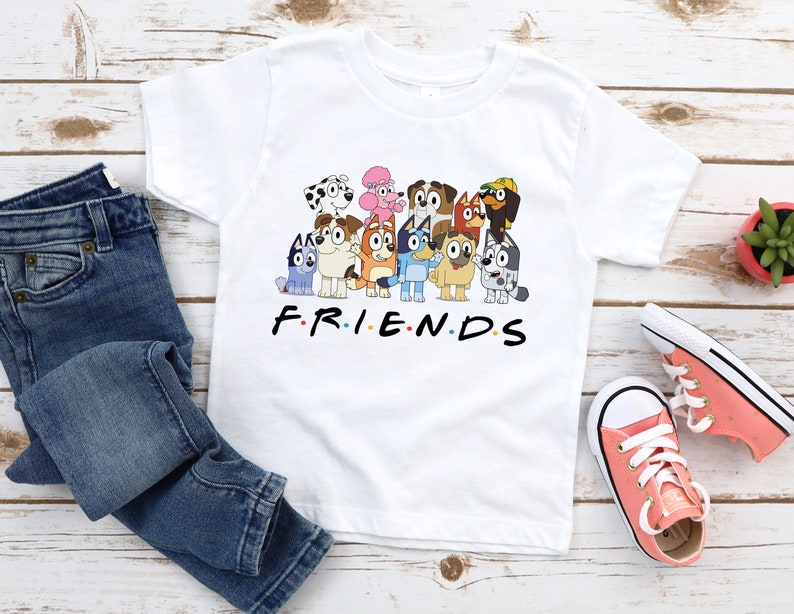May include: White t-shirt featuring a graphic of cartoon dogs from the show "PAW Patrol" and the text "F.R.I.E.N.D.S".