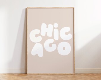 May include: A framed print with a light brown background and white text that reads "CHICAGO" in a playful, rounded font.