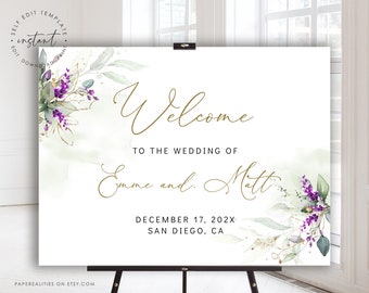 May include: A white wedding welcome sign with gold calligraphy that reads "Welcome to the wedding of Emme and Matt" with the date "December 17, 202X" and location "San Diego, CA". The sign is decorated with watercolour greenery and purple flowers.