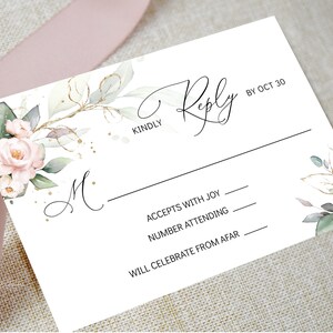 May include: A white RSVP card with a floral design featuring pink roses and green leaves. The card has a black line and the text "KINDLY Reply BY OCT 30". The card also has the text "ACCEPTS WITH JOY", "NUMBER ATTENDING", and "WILL CELEBRATE FROM AFAR" with lines for writing.