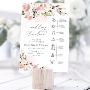 Op de afbeelding: Een roze en witte bloemen-huwelijkstijdlijn-bord met de tekst "wedding timeline" en "Welcome to our wedding Harlow & Ethan December 17, 2022 Thank you for celebrating with us". Het bord geeft de huwelijksgebeurtenissen weer met pictogrammen en tijden.
