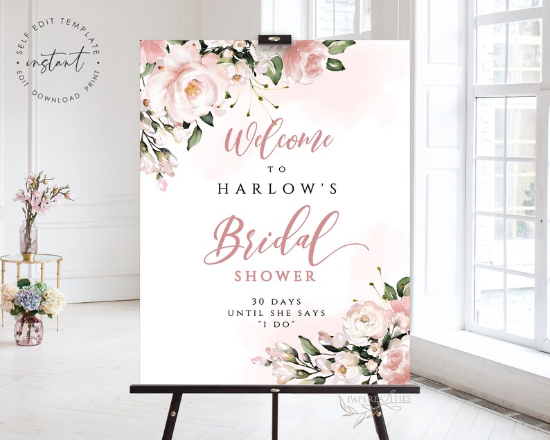Op de afbeelding: Een wit welkomsbord voor een bruiloft met roze aquarelbloemen en de tekst "Welkom op de bruiloft van Harlow 30 dagen tot ze "Ja" zegt"