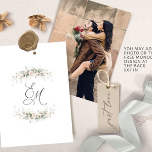 May include: A white card with a watercolour floral wreath and the initials "EM" in black calligraphy. The card is 5x7 inches and can be personalised with a photo or monogram. The text "just love" is written on a small brown tag.