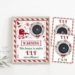 以下が含まれることがあります： 赤と緑のストライプの背景に、「この家はELFの監視下にあります」という警告が書かれた印刷可能なサイン。サインには、漫画のエルフ、カメラレンズが付いたリース、赤い枠の中に「WARNING」という文字が書かれている。また、「ELF CAM」とリースとカメラレンズが描かれた印刷可能なカードが2枚ある。