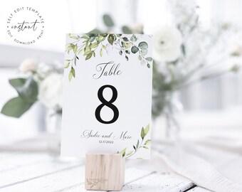 May include: White table number card with green watercolor foliage, the text "Table 8" and "Sadie and Marc 12.17.2022".