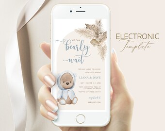 Può includere: Un invito digitale per un baby shower con un adorabile orso dei cartoni animati che indossa una tutina blu con cappuccio. L'invito ha uno sfondo beige con un design a foglia di palma marrone chiaro e il testo "We can bearly wait" in un font corsivo. L'invito include anche il nome del bambino, Lucas, la data e l'ora del baby shower e la posizione. Il testo "registered at babylist.com" è incluso anche.